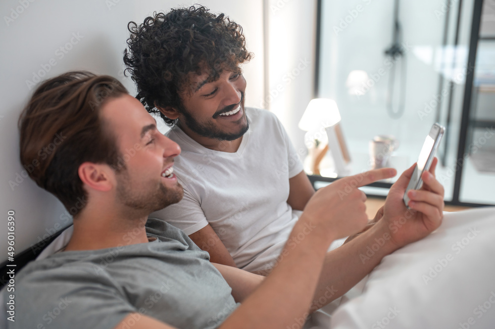 Male showing photos on the cellphone to his partner Male showing photos on the cellphone to his partner