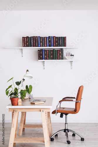 Table and books on shelves hanging on wall in interior of room © Pixel-Shot
