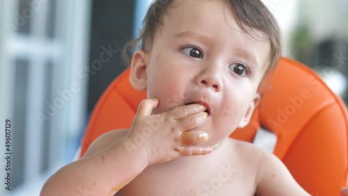 Close-up of a child trying a tangerine for the first time, the Kid takes a slice of tangerine with his fingers and bites it, after which he winces at the sour taste and drops a citrus fruit.