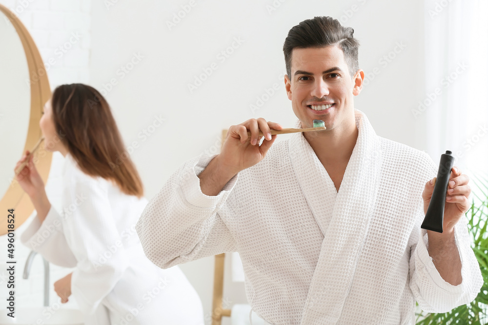 Fototapeta premium Young couple brushing teeth with activated charcoal tooth paste in bathroom