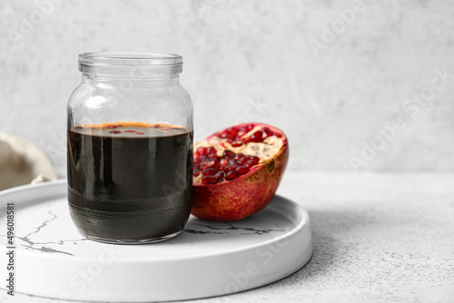 Jar of pomegranate molasses on light background photo