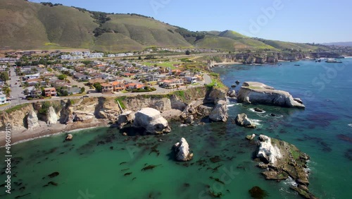Picturesque town along California coast overlooking the vivid blue Pacific Ocean from up on cliffs (Aerial 4K drone footage) photo