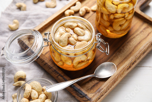 Jars of tasty cashew nuts with honey on table