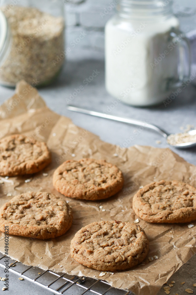 baked oatmeal cookies on baking rack with milk and oats, grey marble table