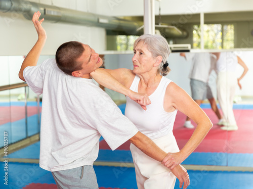 Canvas Print Senior woman exercising elbow strike on man during self-protection training