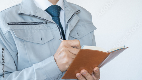 Canvas Print 作業服にネクタイの男性。手帳にメモを書き込む。建設業イメージ。