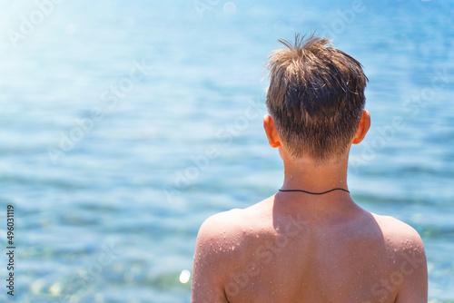  handsome teenage boy on the beach in a swimsuit looks at the sea. Attractive young man on the background of the sea. © Sergey