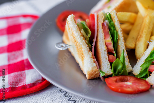 4 club sandwich slices laid out on a gray plate with tomatoes and fries.
