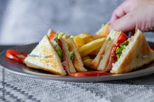 4 club sandwich slices laid out on a gray plate with tomatoes and fries.