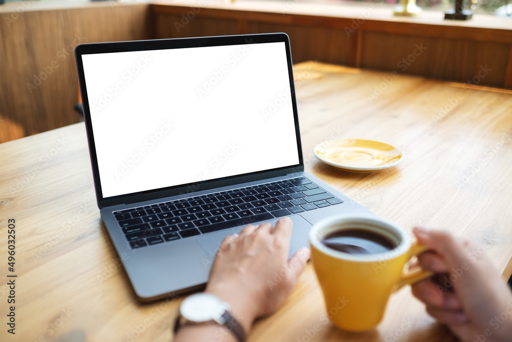 Mockup image of a woman using and working on laptop computer with blank white desktop screen while drinking coffee Mockup image of a woman using and working on laptop computer with blank white desktop screen while drinking coffee