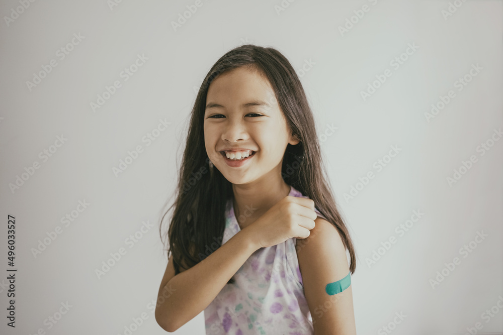 Mixed Asian preteen girl showing her arm with bandage after got vaccinated or inoculation, child immunization, covid omicron vaccine concept - obrazy, fototapety, plakaty 