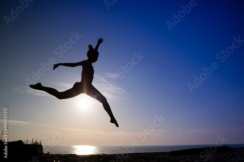 Dance jump performed outdoors in backlight