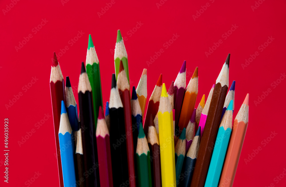 A bunch of colorful pencils on red background A bunch of colorful pencils on red background