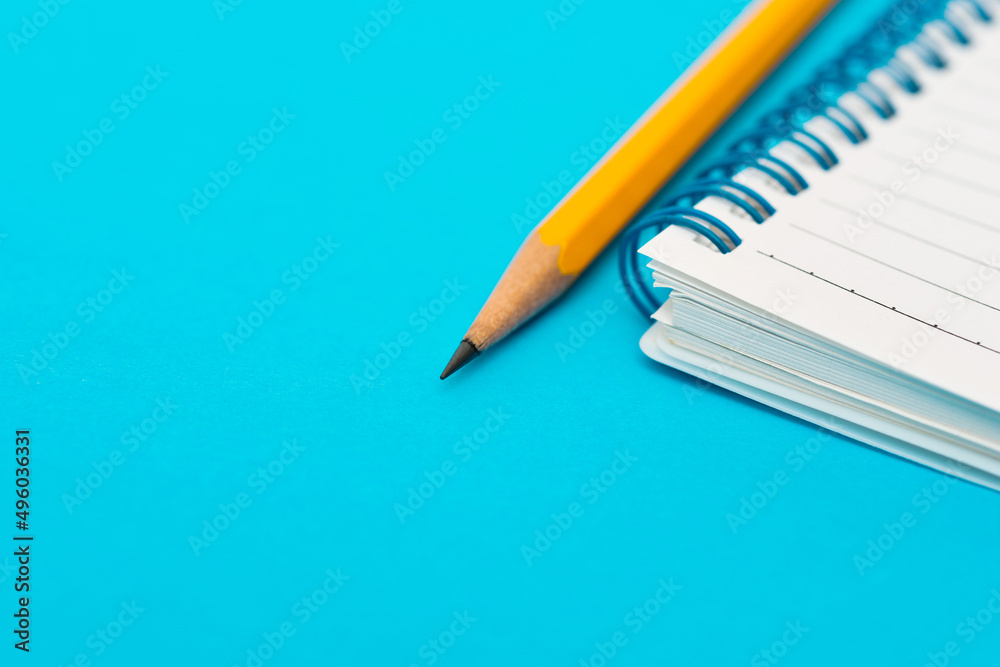 Pencil and notebook on blue background