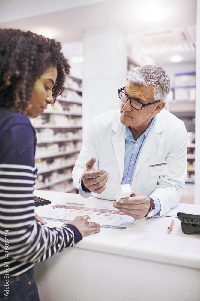 Obraz premium Just take these twice a day. Shot of a dedicated mature male pharmacist giving a customer prescription meds over the counter.