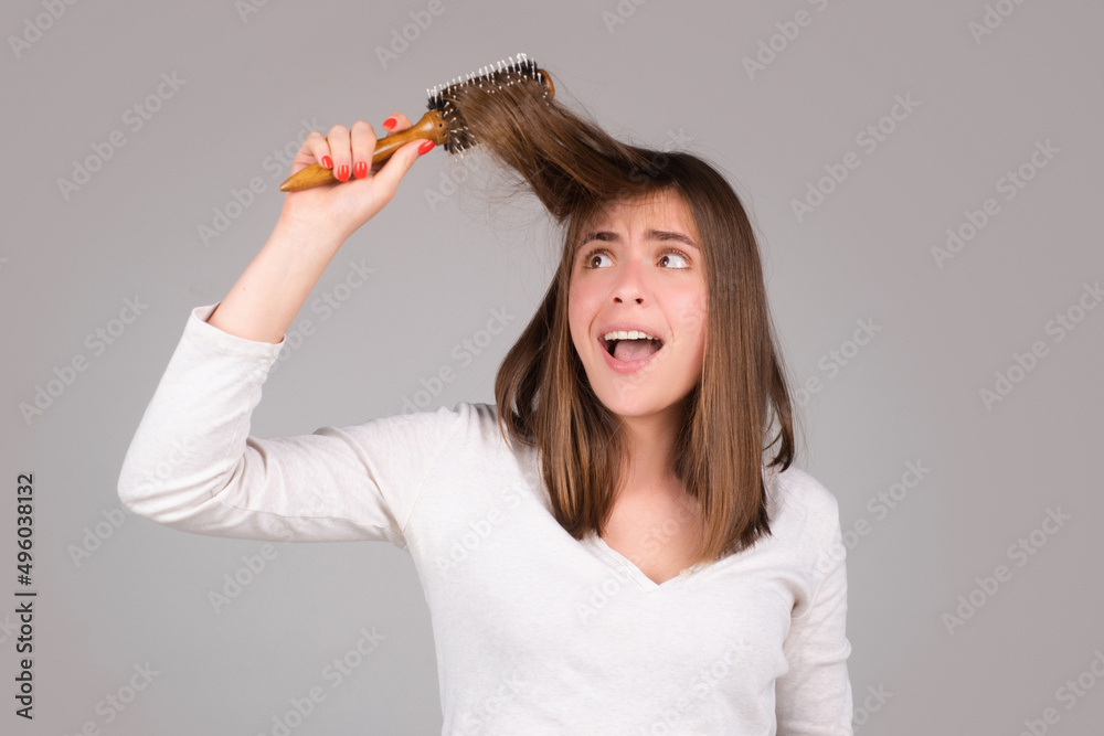 Excited funny woman combing hair. Portrait of female model with a comb brushing hair. Girl with hairbrush, hair care and beauty. Morning routine. Excited funny woman combing hair. Portrait of female model with a comb brushing hair. Girl with hairbrush, hair care and beauty. Morning routine.