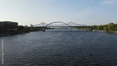 Flying down the main channel of the Mississippi River toward the big blue bridge in La Crosse, Wisconsin. Sun reflecting off the water. Trees on both sides. Bluffs in the distance. 