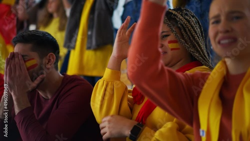 Dissapointed football fans supproting spanish national team in live soccer match at stadium.