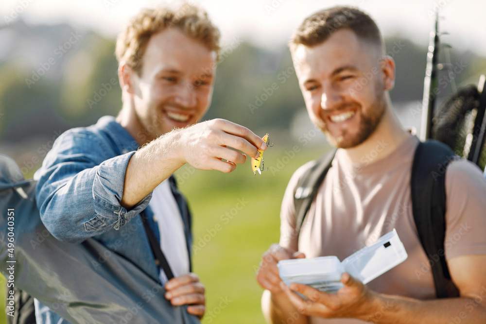 Two men talking and carrying fishing equipment outdoors Two men talking and carrying fishing equipment outdoors