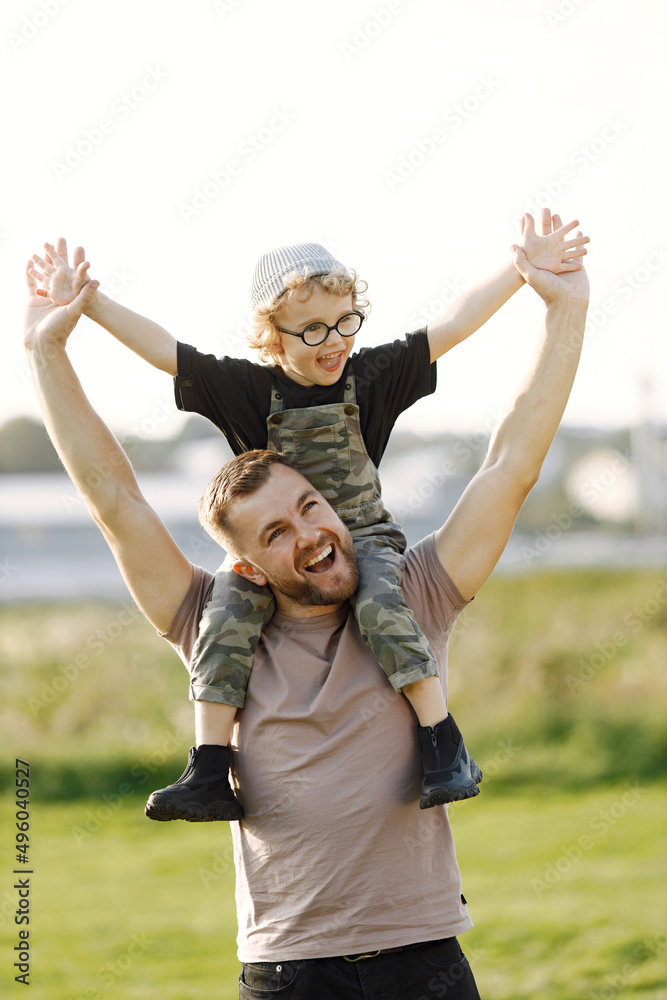 Portrait of father holding his son on a shoulders outdoors