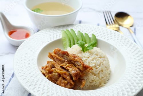 Hainanese fried chicken over oily rice with chili sauce in white plate - Famous Singaporean food and in Thai called Khao Mun Gai Tord