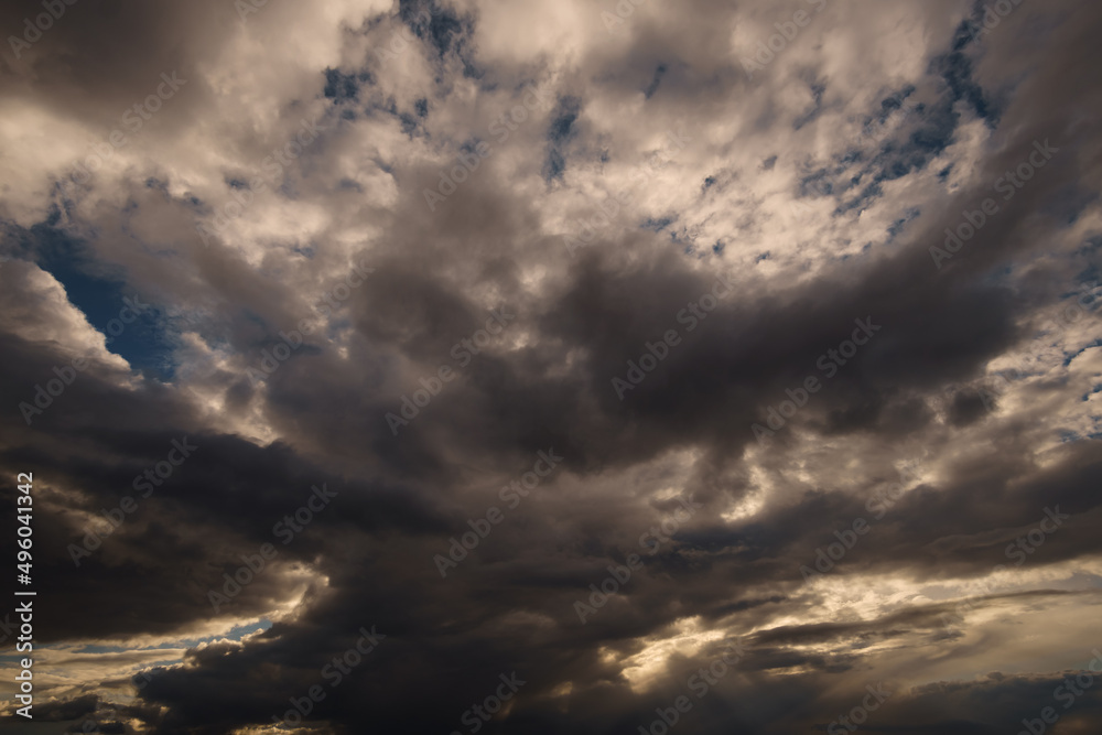 dark dramatic sky, bright sunlight and black silhouette of clouds as background