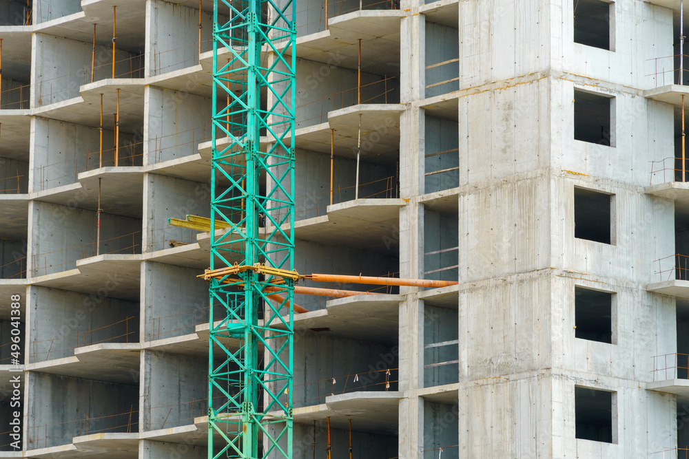construction of a modern high-rise building, the creation of a concrete frame, building materials and a construction crane