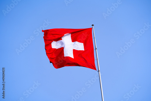 Swiss flag waving on top of building at City of Lausanne on a sunny spring day. Photo taken March 18th, 2022, Lausanne, Switzerland.