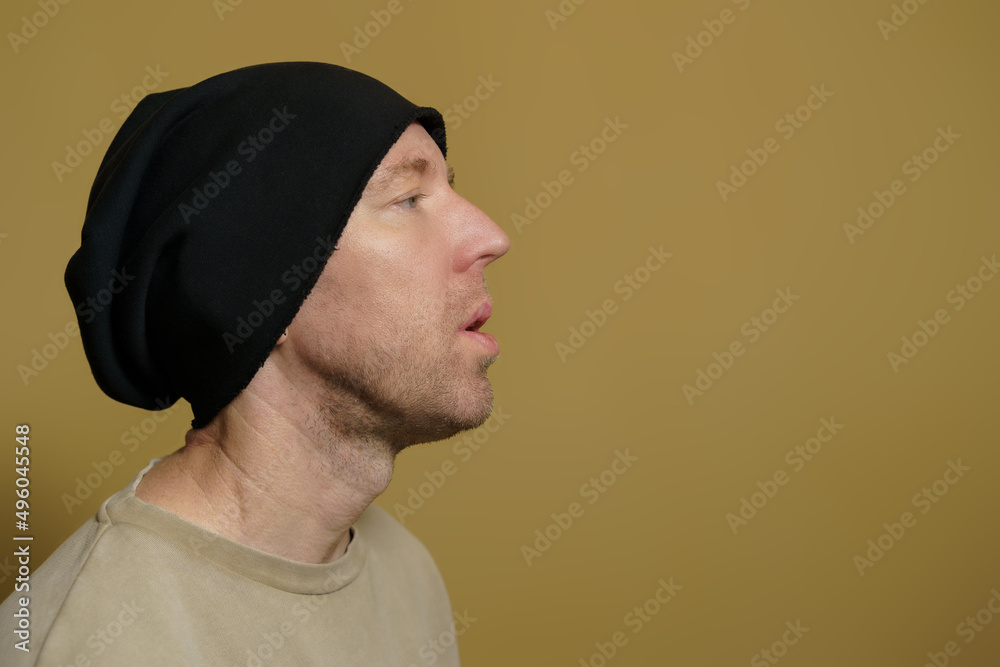 A man in a black hat lets out a cloud of smoke. Close-up portrait of a white man in a black cap