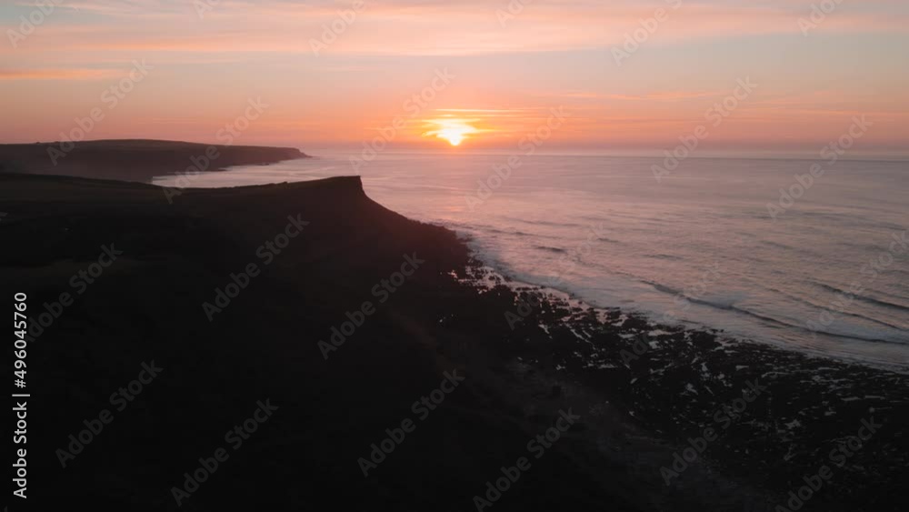AERIAL: Slo-motion sideways pan revealing coastline and orange sunrise backdrop, Rhossili Gower, 4k Drone AERIAL: Slo-motion sideways pan revealing coastline and orange sunrise backdrop, Rhossili Gower, 4k Drone
