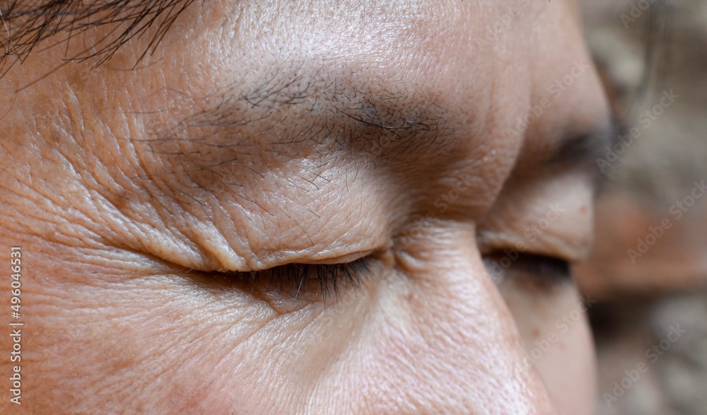 Wrinkles around closed eye of Asian elder man. Wrinkles around closed eye of Asian elder man.