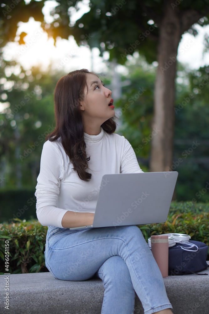 Cute young Asian female student working on a laptop computer outdoors, studying concepts, working in the public domain. Cute young Asian female student working on a laptop computer outdoors, studying concepts, working in the public domain.