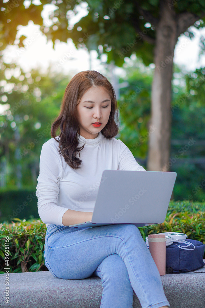 Cute young Asian female student working on a laptop computer outdoors, studying concepts, working in the public domain. Cute young Asian female student working on a laptop computer outdoors, studying concepts, working in the public domain.