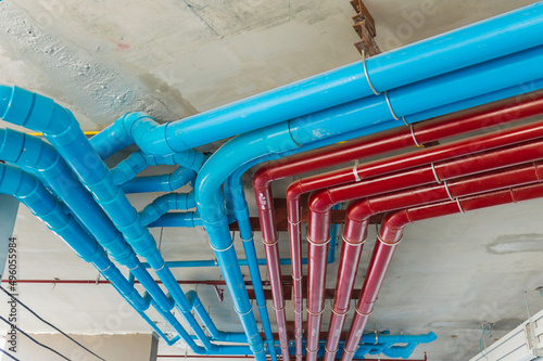 Red fire water pipes on the concrete wall in the condo building.Installation of drainage pipes in the building.Sanitary system of a condominium.water piping system install with the concrete ceiling.