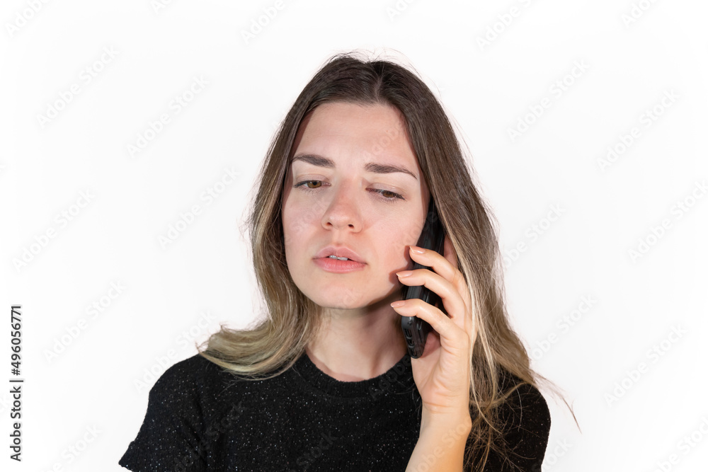 Young woman talking something serious on the phone. Serious face expressions. It's like she got bad news.Isolated white background. Young woman talking something serious on the phone. Serious face expressions. It's like she got bad news.Isolated white background.