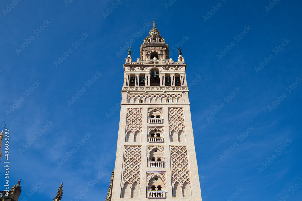 Monument of the giralda of seville in the gothic cathedral. It can be seen rising into the blue sky of the city. It is the largest religious building in the world. Tourism and travel concept.