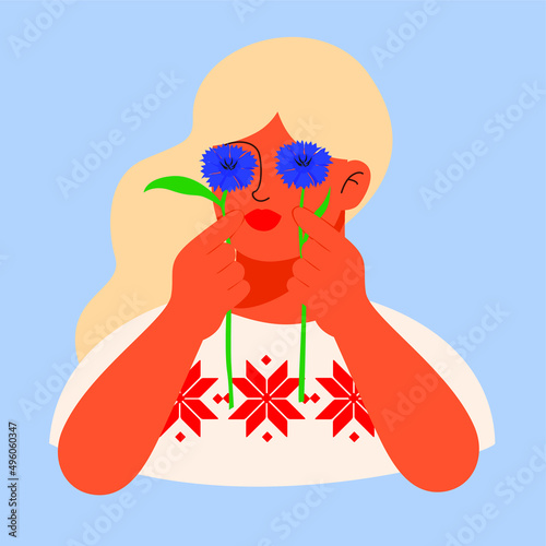 Cute blonde girl holding cornflowers. A Slavonian, Belarusian or Ukrainian woman with an embroidery ornament on a T-shirt.
