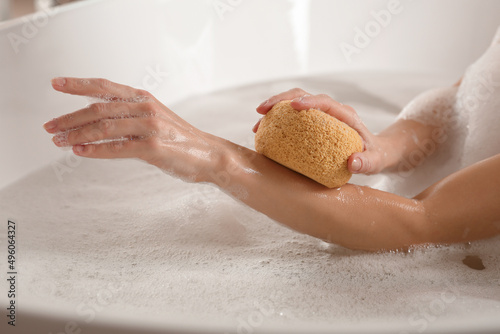 Woman rubbing her forearm with sponge while taking bath, closeup