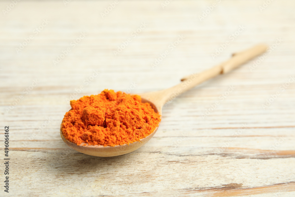 Spoon with saffron powder on white wooden table