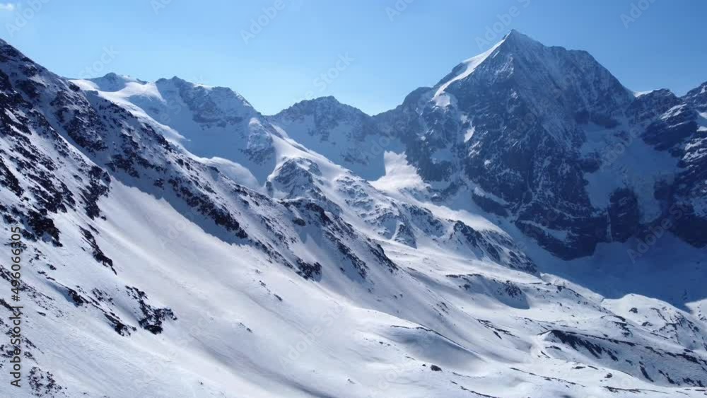 Aerial drone footage of forward flight over scenic snowy mountain range in winter in the European Alps