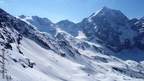 Aerial drone footage of forward flight over scenic snowy mountain range in winter in the European Alps