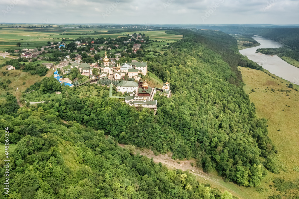 An amazing aerial view of the old St. John the Theologian Monastery in the village of Khreshchatyk, Ternopil region, on a steep hillside with a forest, the Dniester River flows below.  Dniester Canyon