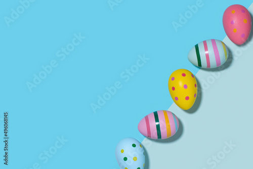 Bright Easter eggs in retro style on a blue background with copy space. Easter eggs in a row diagonally on a two-tone backdrop in blue hues. Happy Easter card.