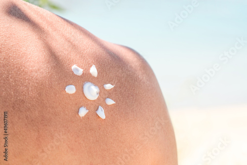 Tanned Shoulder and Applying Sun Cream In Form Of The Sun By The Sea In The Nature. Skin and Body Care.