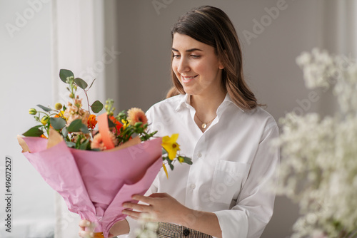 people, gardening and floral design concept - happy smiling woman or floral artist with bunch of flowers at home