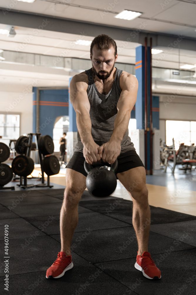 man doing exercises with kettlebell in the gym