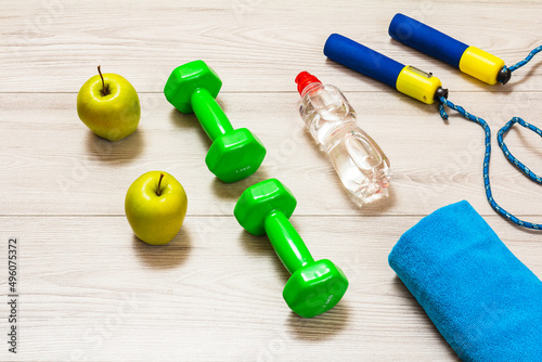 Towel and different tools for fitness on floor in room.