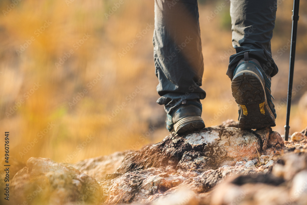 Close up mountaineering boots walking on rocky mountains at  outdoor. Tourist walks on adventure trip in natural at holidays. Travel lifestyle concept