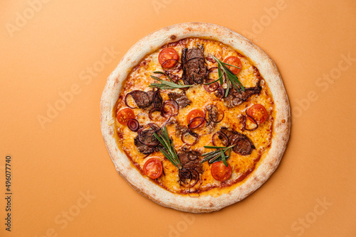 Pizza Grill with veal fillet, blue onion with cherry tomatoes, mozzarella cheese paired with gouda cheese. Beige background. Copy space