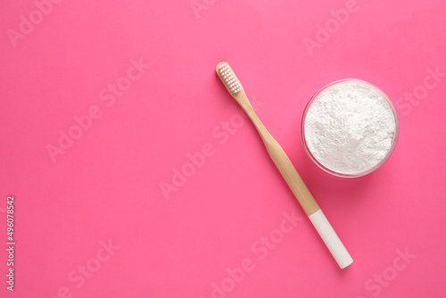 Bowl of tooth powder and brush on pink background, flat lay. Space for text
